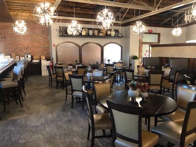 Dining room of a resturaunt with round chairs and chandelier lighting.