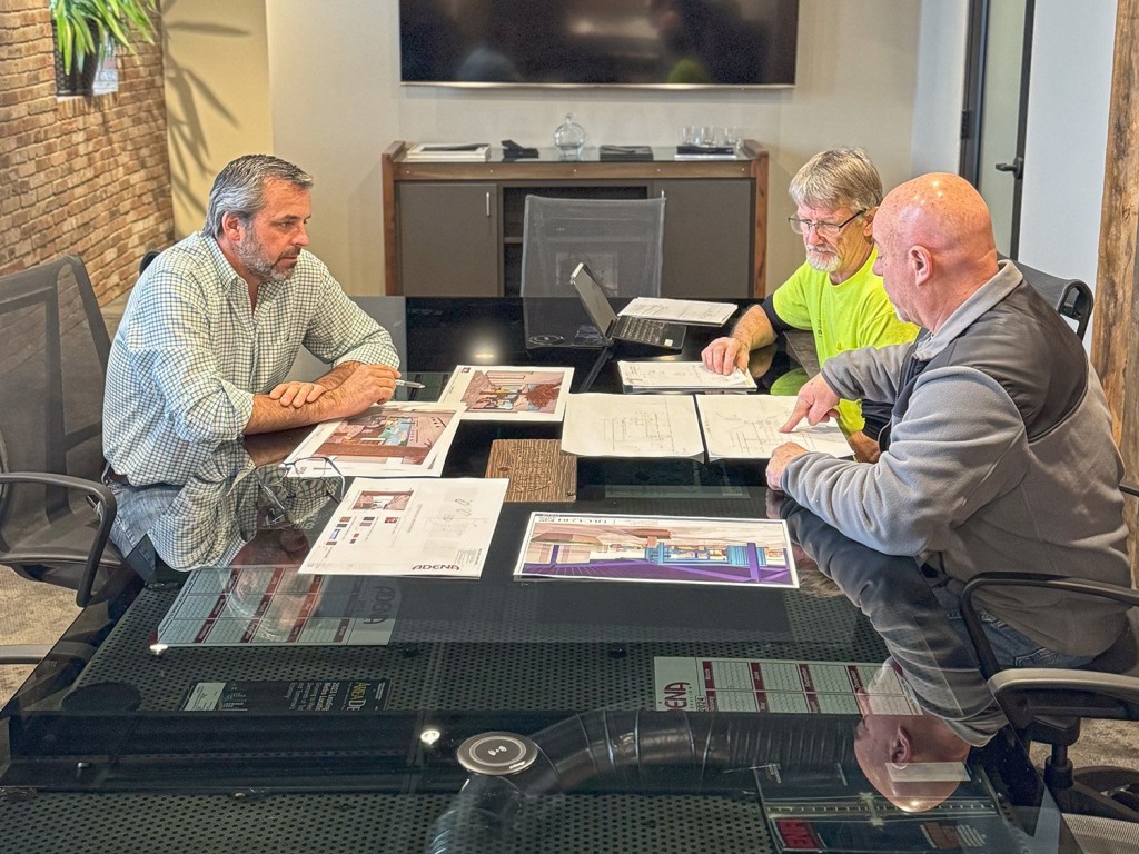 Group of people sitting around table looking at construction plans and mockups