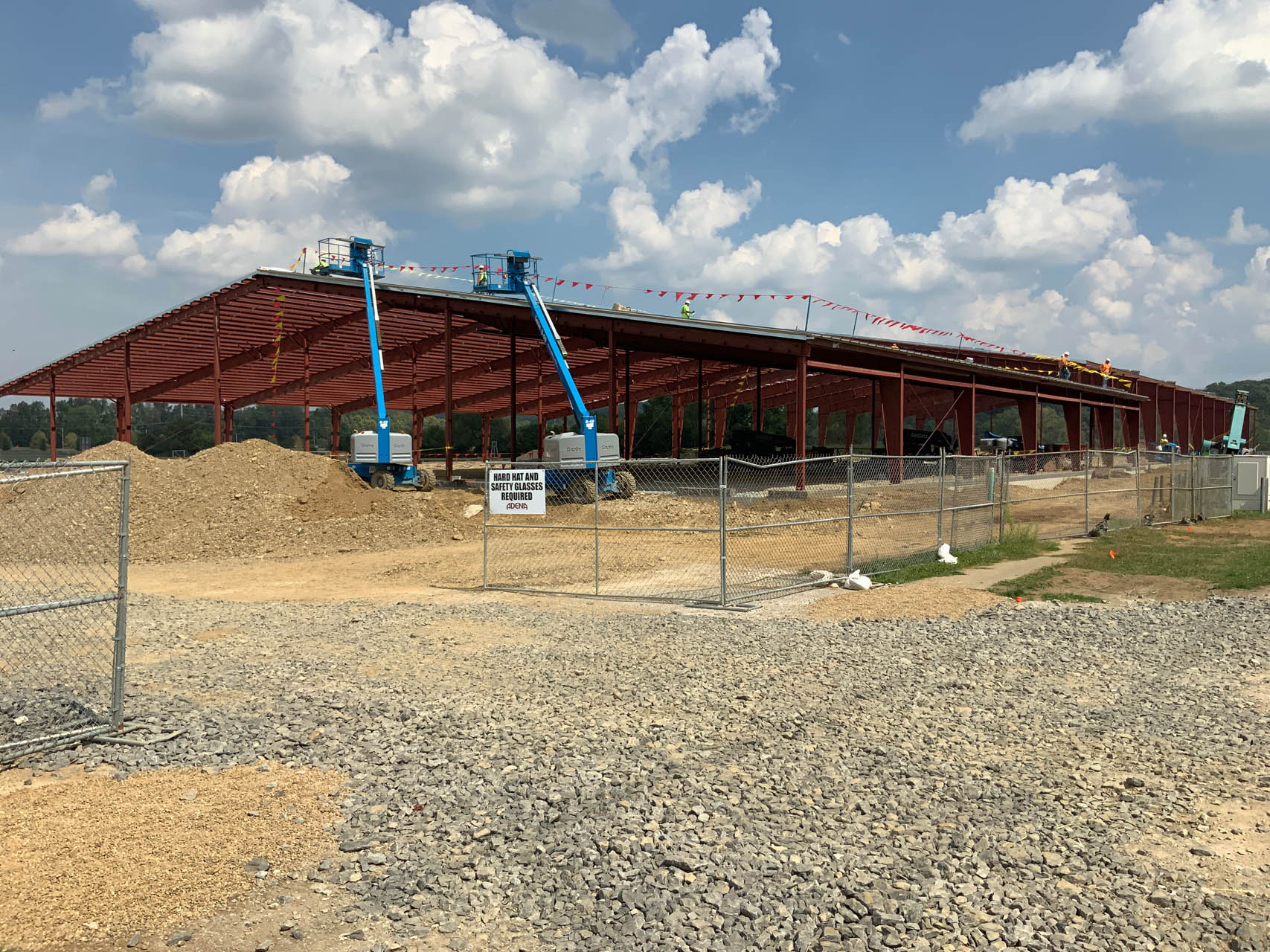 Steel-framed building under construction at a fenced jobsite.