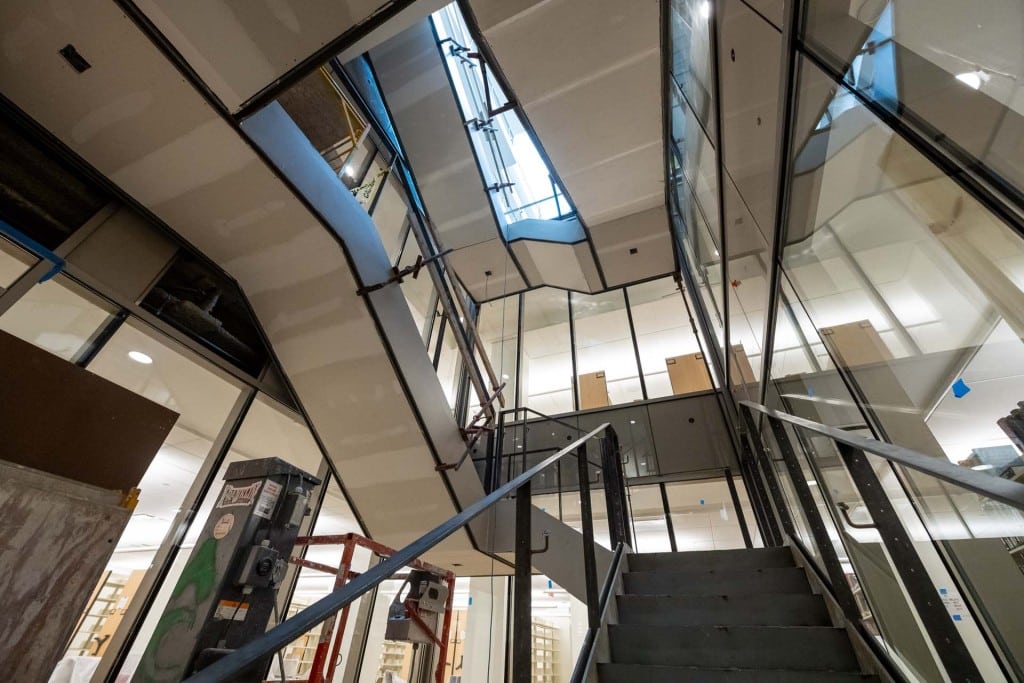 Interior construction stairwell with glass partitions and a skylight above.