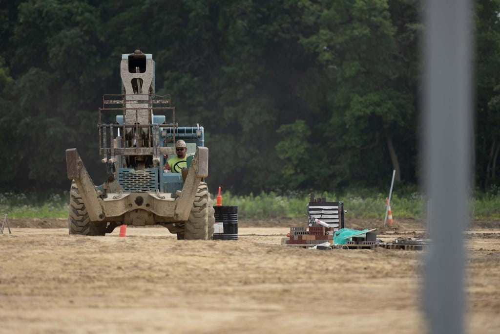 Forklift-style construction equipment on a dirt jobsite with materials stacked nearby.