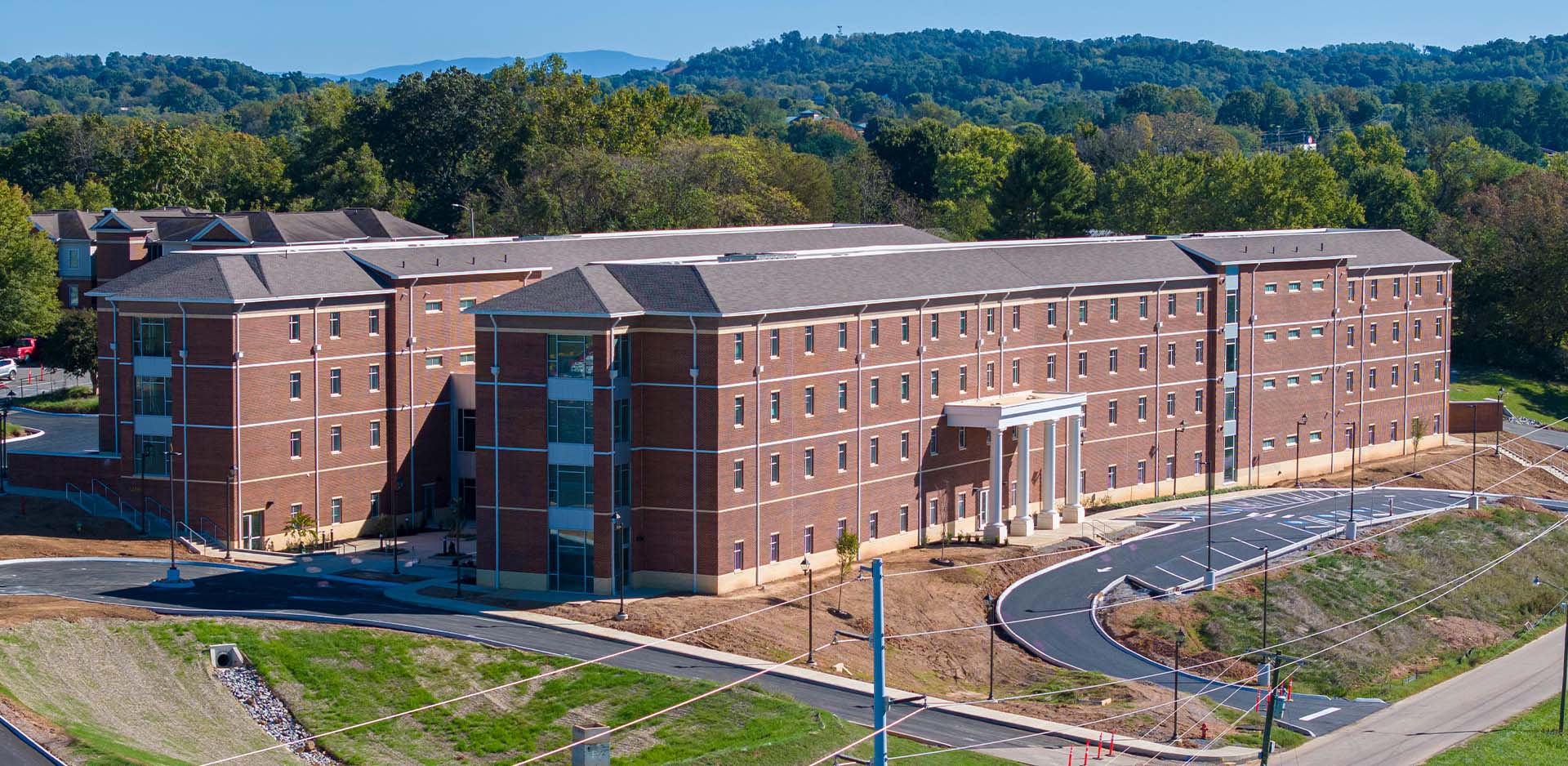 A large multi-story brick building with a columned entrance and curved driveway.