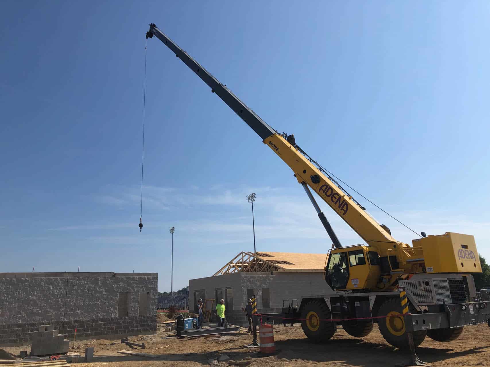 Yellow crane lifting a load at a construction site.