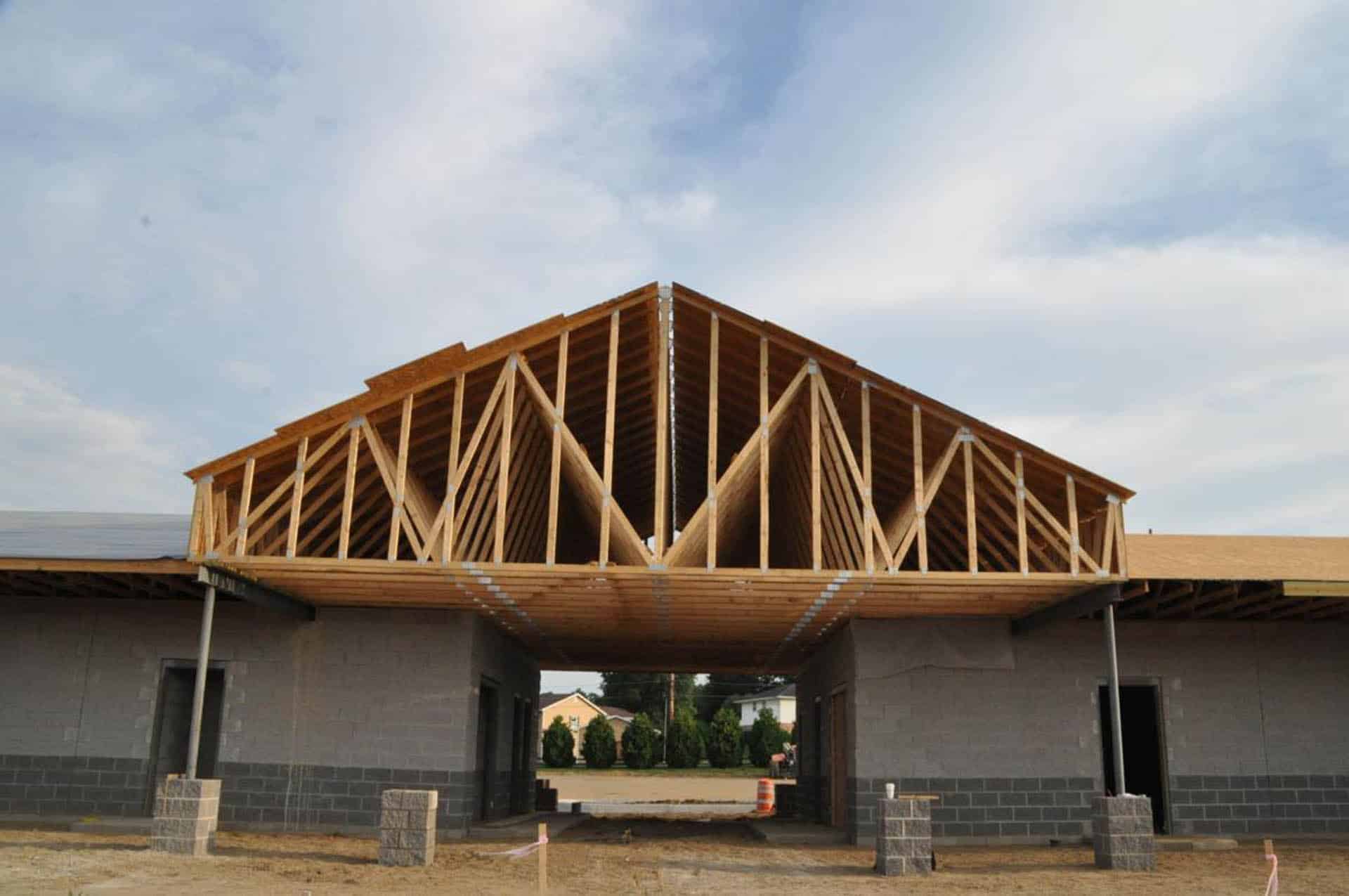 Framed roof trusses over a partially built pavilion with concrete block walls.